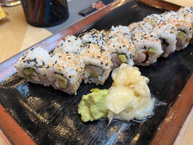 Japon restoranındaki suşi rulosunu siyah tabakta kapat.