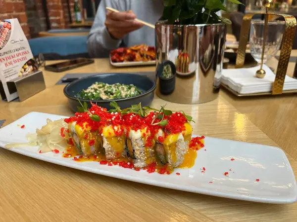 Kaunas, Litvanya. 26 Ocak 2025. Japon restoranının masasında Kızıl Ejder Suşi, yosun salatası ve tanınmamış bir adam var. Afiyet olsun.