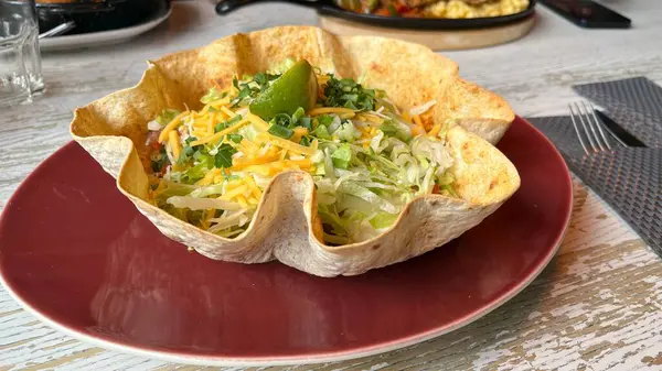Kızarmış tavuklu sebzeli burrito kasesi. Etli, peynirli, marullu ve limonlu burrito kasesi tortilla kasesinde sunuluyor. Yemek hazır, restoran yemeği, sağlıklı yemek.