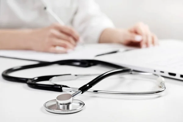 Yeni bir hasta için anket dolduran bir doktorun arka planında telefon dosyası var.