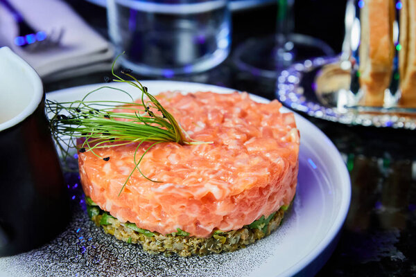 Salmon tartare with avocado on a white plate in a restaurant. Close-up, selective focus