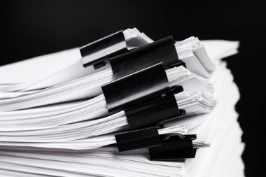 Bazıları siyah klasörlerle tutturulmuş bir yığın ofis kağıdı.