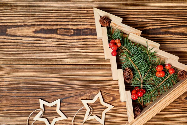 Dřevěný Vánoční Stromek Jedlovými Větvemi Uvnitř Zdobené Bobulemi Dřevěném Pozadí — Stock fotografie