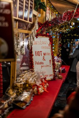 Bayram süslemeleri ve ikramlar ile çevrili, sıcak şarap ve patates gözlemeleriyle dolu bir menü sunan şenlikli Noel tezgahı.