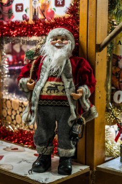 Festive Christmas market stall featuring a Santa figurine, and colorful holiday decorations in a cozy nighttime setting clipart