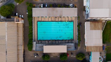 Aerial view of a vibrant outdoor swimming pool amidst urban structures, capturing the essence of community recreation. High quality photo clipart