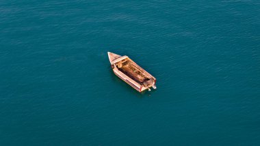 Sakin, mavi engin bir açık denizde yüzen ıssız ahşap bir tekne huzur ve izolasyon hissi uyandırıyor. Yüksek kalite fotoğraf