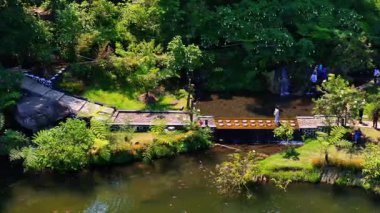 Bereketli bir nehir kenarı parkı, yemyeşil bir köprü, küçük bir şelale ve Endonezya 'daki huzur ortamının tadını çıkaran ziyaretçiler.