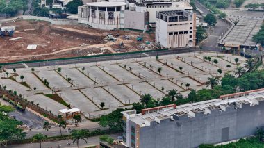 Şantiyeye ve modern binalara bitişik büyük, boş bir otoparkın havadan görünüşü kentsel gelişimi gösteriyor. Yüksek kalite fotoğraf
