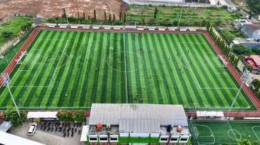 Canlı yeşil çizgili bir futbol sahasının, koşan raylar ve kentsel yapılarla çevrili halinin havadan görüntüsü. Yüksek kalite fotoğraf