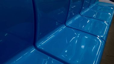 Pürüzsüz kıvrımları ve yansıtıcı renkleriyle parlak, parlak, parlak bir plastik koltuğun soyut yakın çekimi modern ve temiz bir estetik yaratıyor. Yüksek kalite fotoğraf