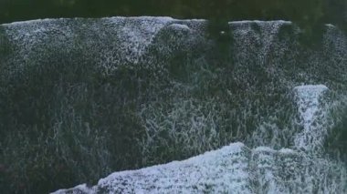 Yukarıdan aşağı statik çekim beyaz kırılan dalgalar ile okyanusun daha koyu yeşil suları arasındaki dinamik etkileşimi yakalar ve soyut desenler ve dokular yaratır. Yüksek kalite 4k görüntü