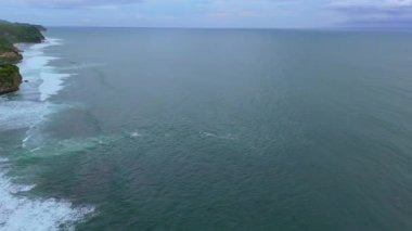 360 derecelik insansız hava aracı, kumlu bir sahili olan uzun ve kıvrımlı bir tropikal kıyı şeridini, dalgaların kıyıya vurmasını, ardından yemyeşil tepelerin yükselmesini ve kıyı şeridi boyunca yuva yapmış bir köyü gösteriyor. Yüksek kalite 4k görüntü