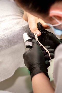 Profesyonel pedikür. Plastik eldiven giyen pedikür uzmanı güzellik salonunda kadın ayak tırnaklarını kesiyor.