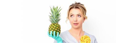 Beyaz arka planda lolipoplu taze ananas tutan beyaz kadın doktor diyetisyen.