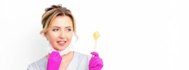 Şekerleme uzmanının elinde sıvı sarı şeker macunu var. Beyaz arka plandaki tahta bir çubukta tüy dökmek için balmumu.