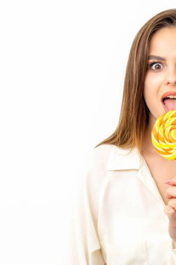Beyaz gömlekli güzel beyaz bir kadın beyaz arka planda lolipop yalıyor.