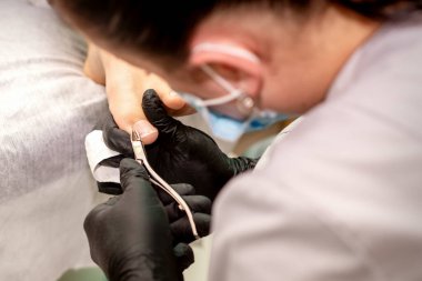 Profesyonel pedikür. Plastik eldiven giyen pedikür uzmanı güzellik salonunda kadın ayak tırnaklarını kesiyor.