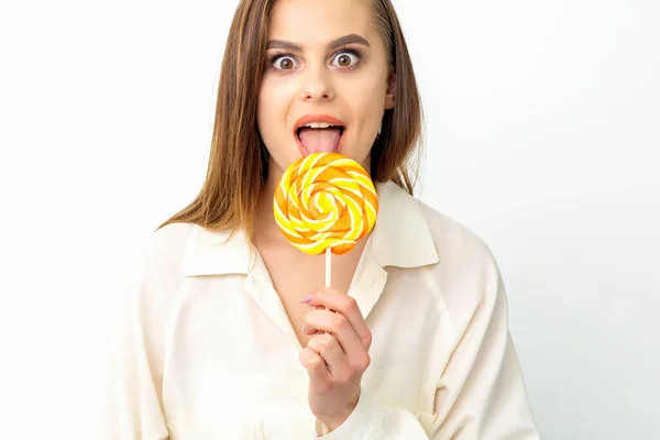 stock image Beautiful young caucasian woman wearing a white shirt licking a lollipop on a white background