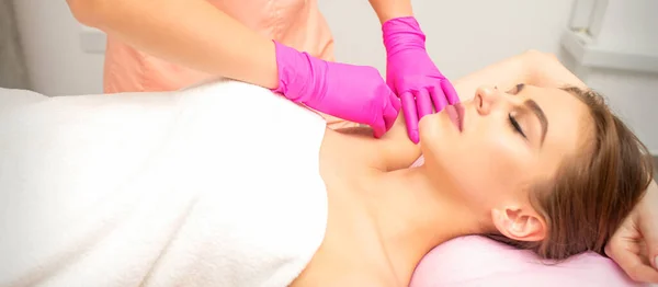 Waxing. Depilation under the armpits of the young woman lying with closed eyes in the spa salon