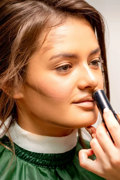 Linda Jovem Morena Recebendo Maquiagem Com Corretor Vara Seu Rosto — Fotografia de Stock