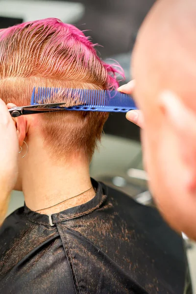 理髪店で男性の美容師によって若い白人女性の短いピンクのぬれた髪を染めのヘアカット — ストック写真