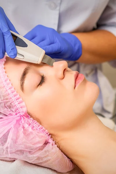 stock image Young caucasian woman receiving facial skin cleaning by ultrasonic cosmetology face equipment in a medical salon