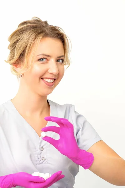 一个年轻 面带微笑的白种人美容师戴着粉色手套拿着糖立方体的画像 在白色背景下看着摄像机 — 图库照片