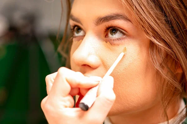 Piękna Młoda Brunetka Kobieta Otrzymuje Makijaż Ukrywaczem Kij Twarzy Salonie — Zdjęcie stockowe
