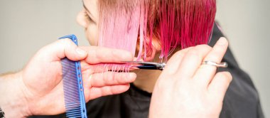 Berber dükkanındaki bir erkek kuaför tarafından boyanmış kısa pembe, ıslak, beyaz kadın saçı.