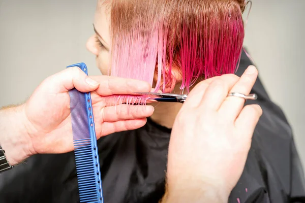 理髪店で男性の美容師によって若い白人女性の短いピンクのぬれた髪を染めのヘアカット — ストック写真