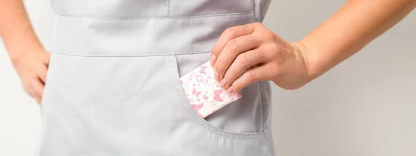 stock image The female hand puts menstrual sanitary pads into her pocket, close up