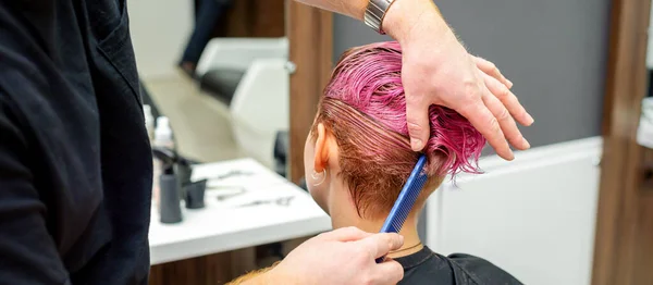 理发店里 一位美发师正在梳理美发师沙龙里一位女性顾客染成的粉色湿透了的短发 — 图库照片