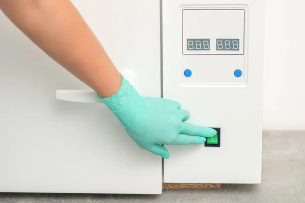 stock image Beautician in protective gloves starts the machine for disinfection of tools before the medical procedure