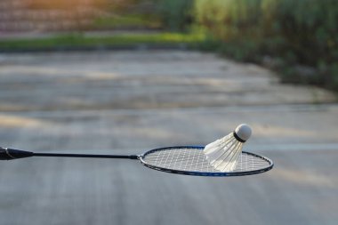 Badminton raketleri üzerinde beyaz krem badminton mekikleri, bulanık ağaçlar arka plan, açık havada badminton oynamak için konsept, yumuşak ve seçici odaklanma.                               