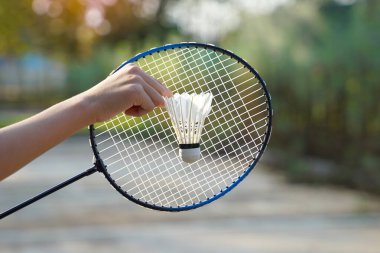 Badminton raketinin önünde bir mekik horozu tutan kişi, boş zamanlarında badminton oynamak için konsept, yumuşak ve seçici odaklanma.                                