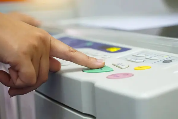 stock image The office secretary presses the button to start the document copying machine to have another copy of the document stored in a file as evidence.                         