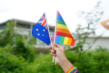 Gökkuşağı bayrağı ve Avustralya 'nın ulusal bayrağı gökkuşağı bileklik takan LGBT insanlarının elinde. yumuşak ve seçici odaklanma.                                