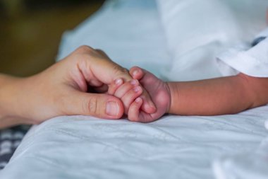 Anne ve bebek el ele tutuşup sevgi ve ilgi gösteriyorlar. Bebek eli kavramı, anne ve bebek, Anneler Günü, bebek, anne.                               