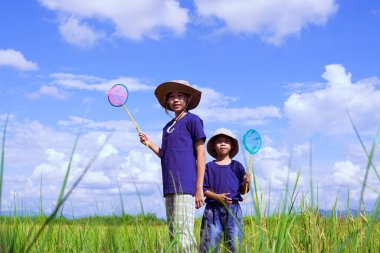 Asyalı erkekler ve kızlar pirinç tarlalarında durup pirinç tarlalarındaki ekosistemi araştırıyorlar. Sınıf dışında öğrenim kavramı, aktiviteler, doğa eğitimi, ekoloji 
