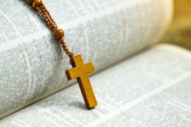 Tahta haç ve tespih bir İncil kitabının üzerinde duruyor. Yumuşak ve seçici odak.                               