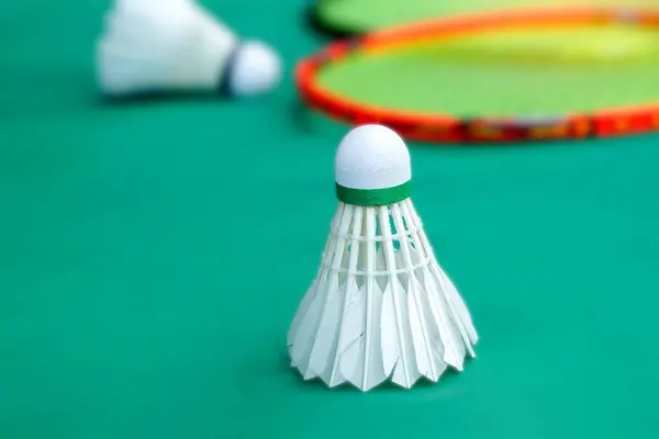 stock image white shuttlecock on green background, blurred badminton racket and white shuttlecocks background. soft and selective focus.                               