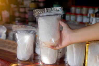 Hand holding a bag containing flower of salt, which is clean and pure organic rock salt. It has higher minerals and nutritional values than normal salt.                                clipart