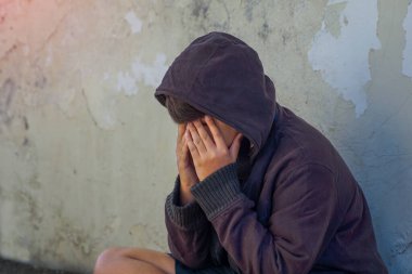 Siyah kapüşonlu genç çocuk ağlarken yüzünü kapattı. Gençlik sorunları, yalnızlık, evsizlik, terk edilme kavramında                               