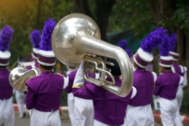 Students carry mellophones in the school orchestra procession It is a medium-pitched brass instrument used in marching bands and is used to play the French horn section in bands and orchestras.                                clipart