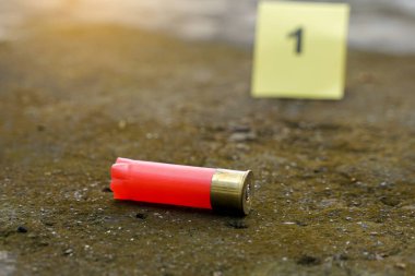 Mermi kovanları beton zemine düşer ve olay yerindeki kanıt numarasının bulanık arkaplanı. Soruşturma kavramı, adli tıp, kanıt, adli tıp..                               