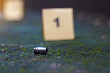 Mermi kovanları beton zemine düşer ve olay yerindeki kanıt numarasının bulanık arkaplanı. Soruşturma kavramı, adli tıp, kanıt, adli tıp..                                 