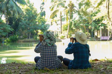 İki Asyalı çocuk okulda yerel kuşları incelemek için dürbün kullanıyor. Yumuşak ve seçici odak.                               