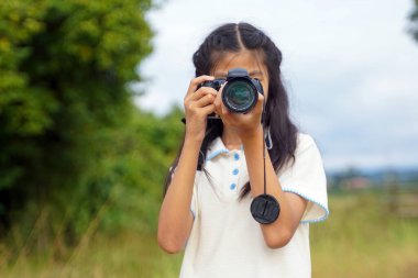 Asyalı kız tarlada doğanın fotoğraflarını çekmek için dijital kamera kullanıyor. Keşif kavramı, sınıf dışında, açık havada, ekoloji, doğa, öğrenme, seyahat.                               