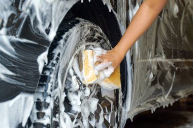 Arabayı yıkamak için köpük sıktıktan sonra arabayı temizlemek ve temizlemek için el ele tutuşan sünger..                               